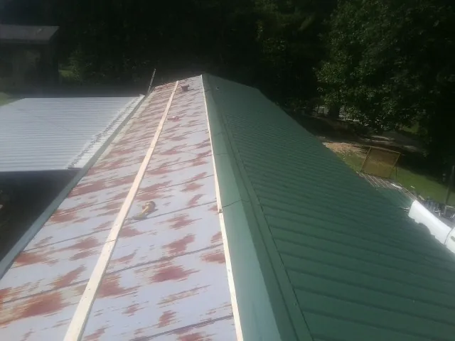 Old rusted panels beside newly installed green metal roofing — Wind Damage Roof Repair by Roofing Brothers in Summit Lake
