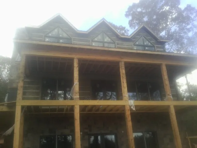 Dormers and porch framing on a large log home under construction — Roof Coating work by our crew in Summit Lake