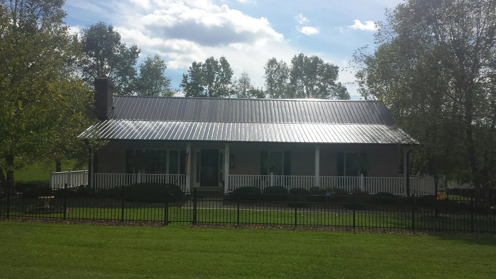 Gray metal roof on a brick ranch with a full width front porch — Gutter Guard Installation work by our crew in Summit Lake