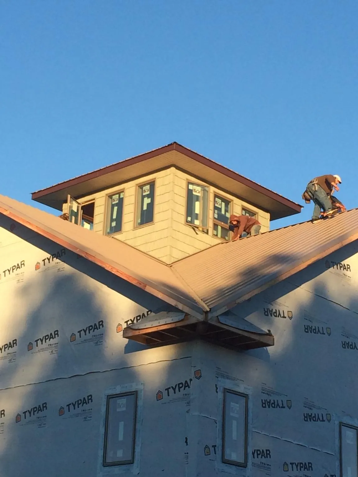 Roofers working around a rooftop cupola on a new metal roof at sunset — Roof Waterproofing in Summit Lake by Roofing Brothers